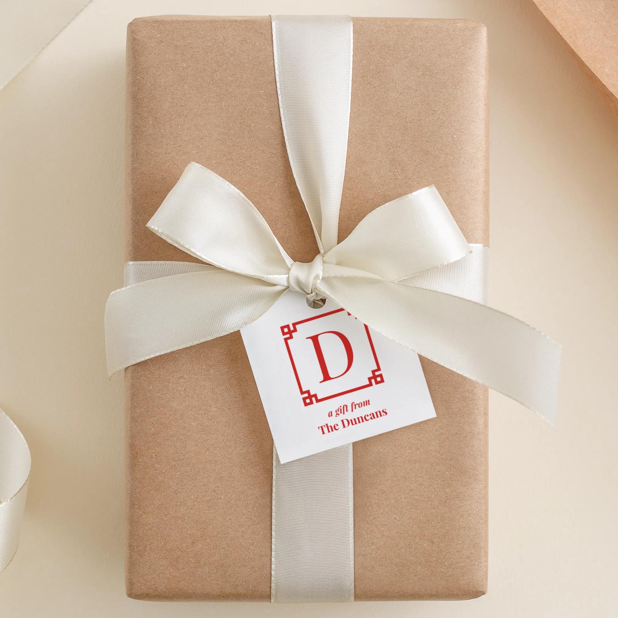 A gift box wrapped in brown paper with a white ribbon and a white tag with a red letter "D" and text that reads "A gift from The Dunns".